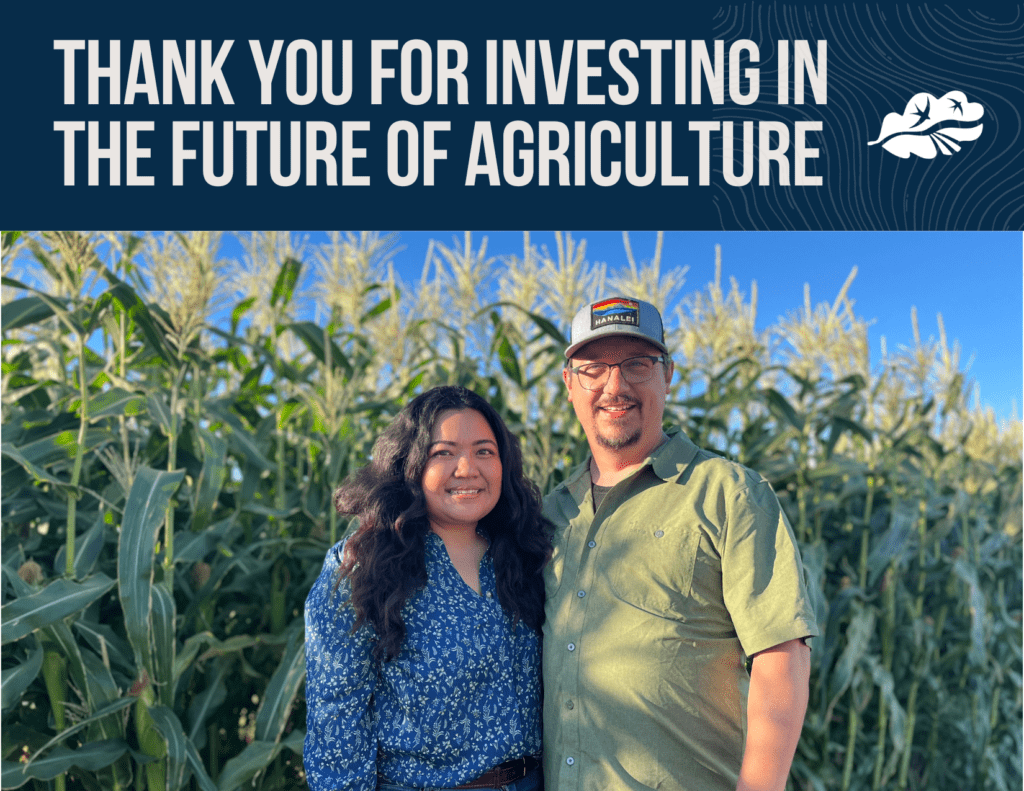 A photo with two people standing in a corn field posing for a photograph